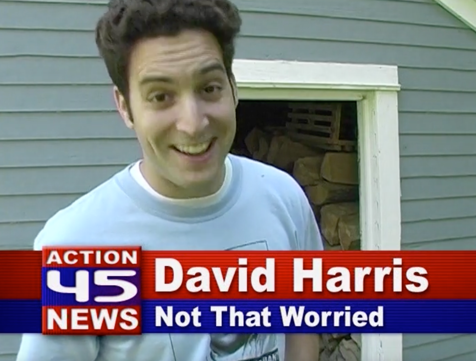 A screenshot from Nate on Drums that shows a man standing in front of a woodshed and smiling. An onscreen graphic below him indicates it's an image from Action 45 News and the man is identified as David Harris. Below his name is the phrase "Not That Worried"