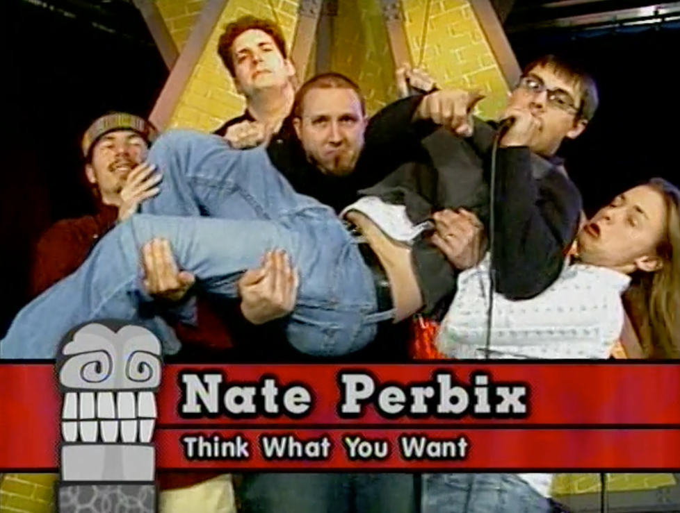 Screenshot from Nate on Drums that shows several people holding up a person who is speaking into a microphone and pointing at the camera. A graphic on screen identifies the person as Nate Perbix and included the line "Think What You Want"