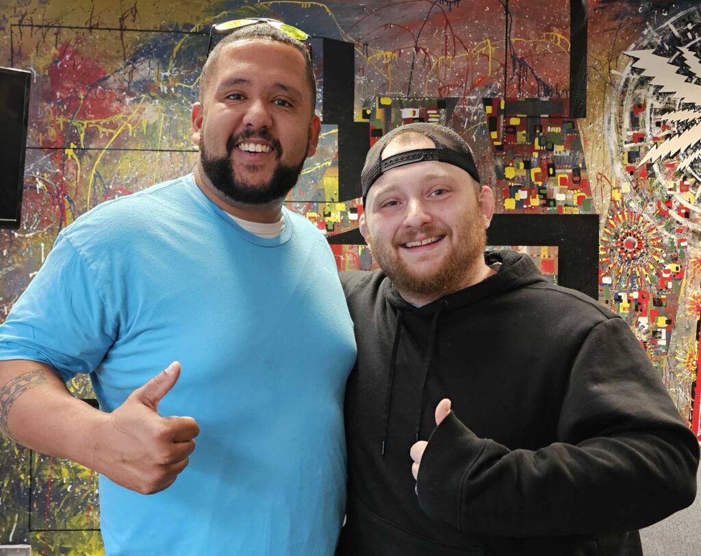 Erick Austin, left, and Jared Loberg, right, stand in front of a mural in the KVSC offices.