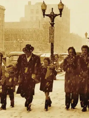 A sepia-toned image of a family walking on a snowy downtown street
