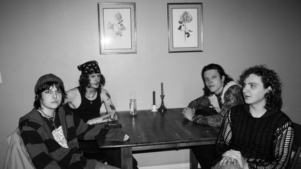 The band members of Mystery Meat sit around a table