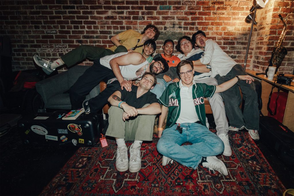 The nine members of Aurora Ave. pile together on a couch