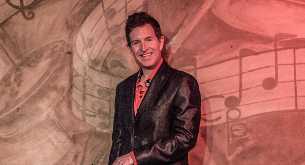 Steve Wynn stands in front of a wall that includes music symbols on it