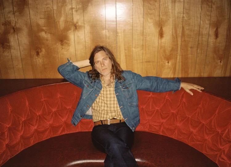 Eric Johnson sits on a red couch